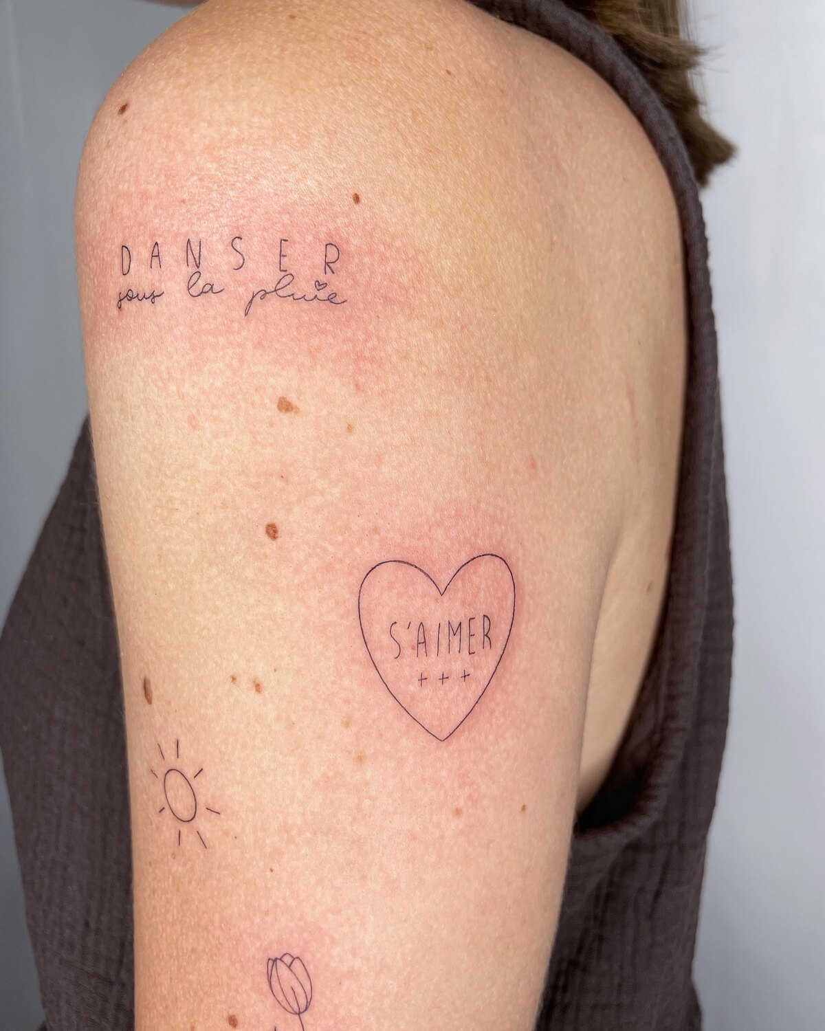 Tatouage coeur et symboles fins sur l'épaule par Lotty